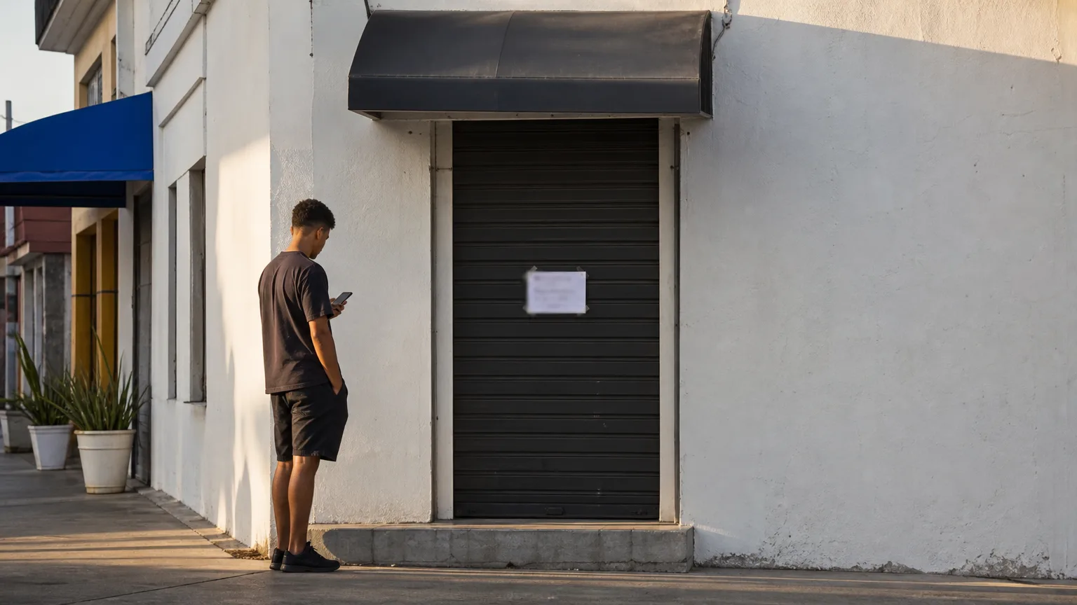 Cliente diante da porta fechada de uma loja olhando o celular